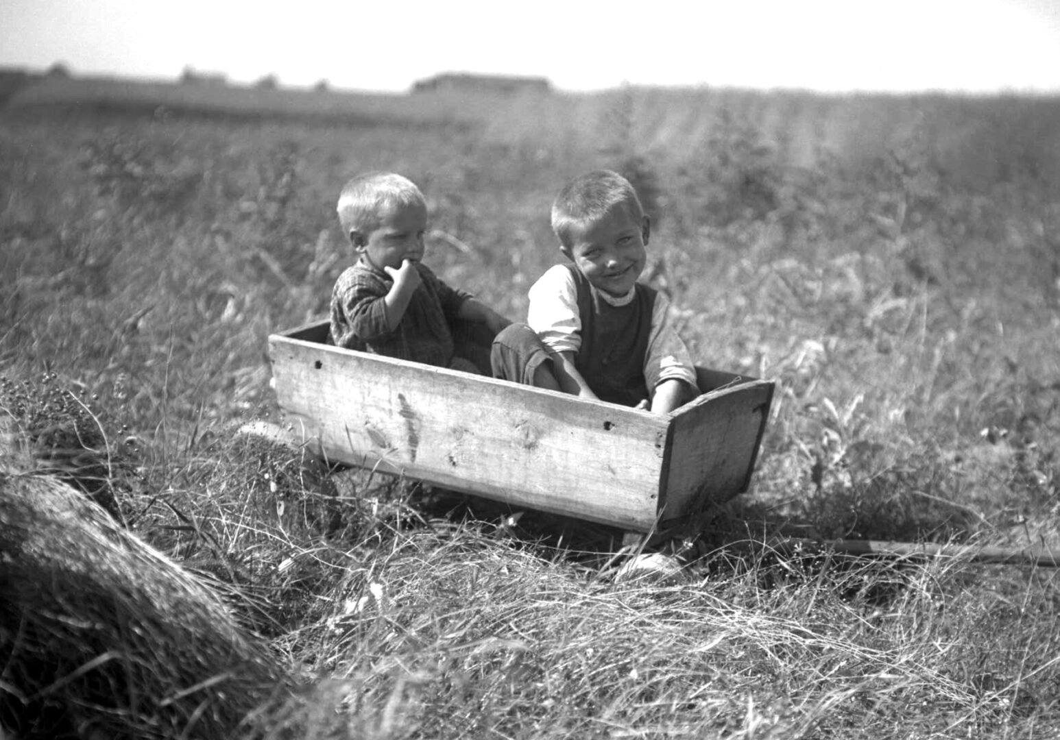 Two boys in a wooden cart.